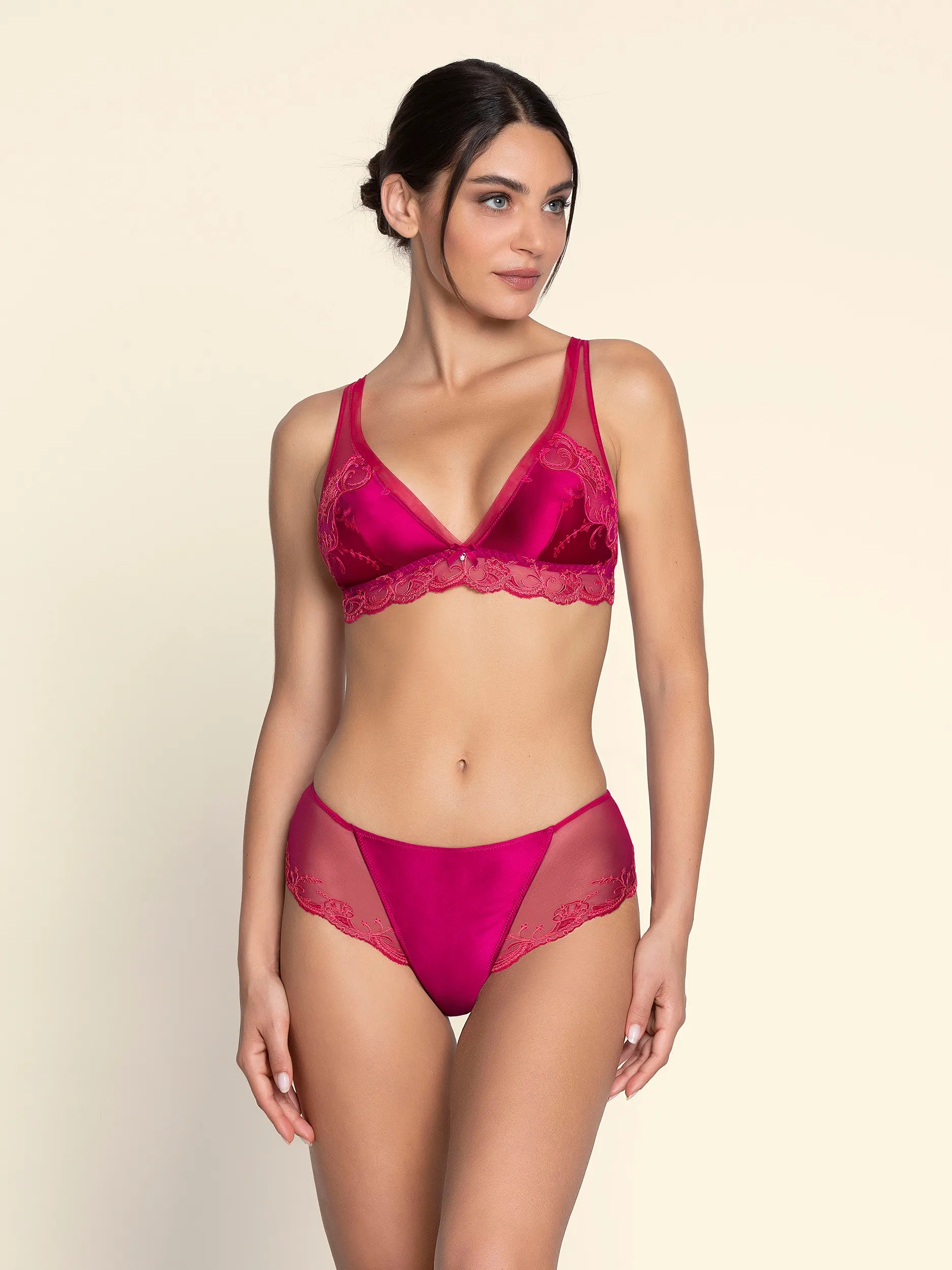 Woman wearing a pink lingerie set on a beige background